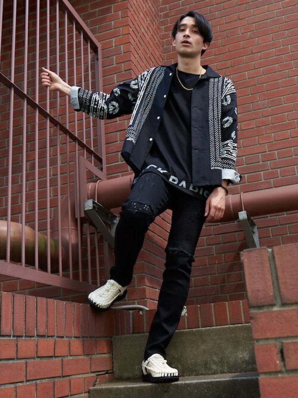 ブラック系のデニムパンツ、ブラック系のTシャツ/カットソー、ゴールド系のネックレスを着用したメンズの春コーディネートの1枚目の写真