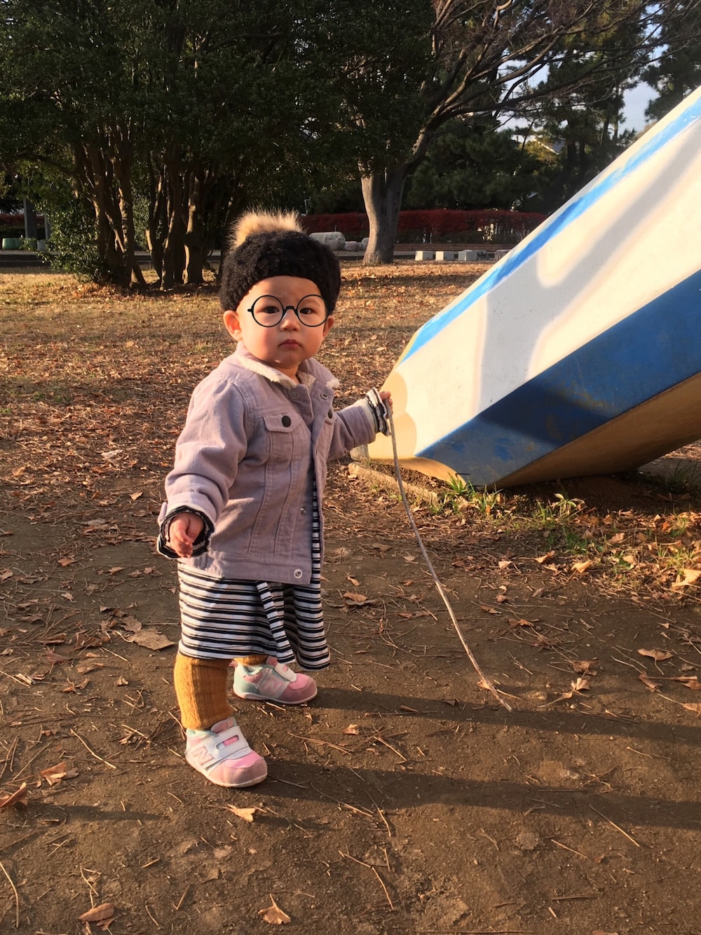 グレー系のデニムジャケット、ブラック系のワンピース、ピンク系のスニーカーを着用したキッズの冬コーディネートの1枚目の写真