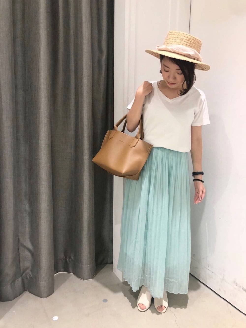 ホワイト系のTシャツ/カットソー、グリーン系のスカート、ベージュ系のサンダルを着用したレディースの春コーディネートの1枚目の写真