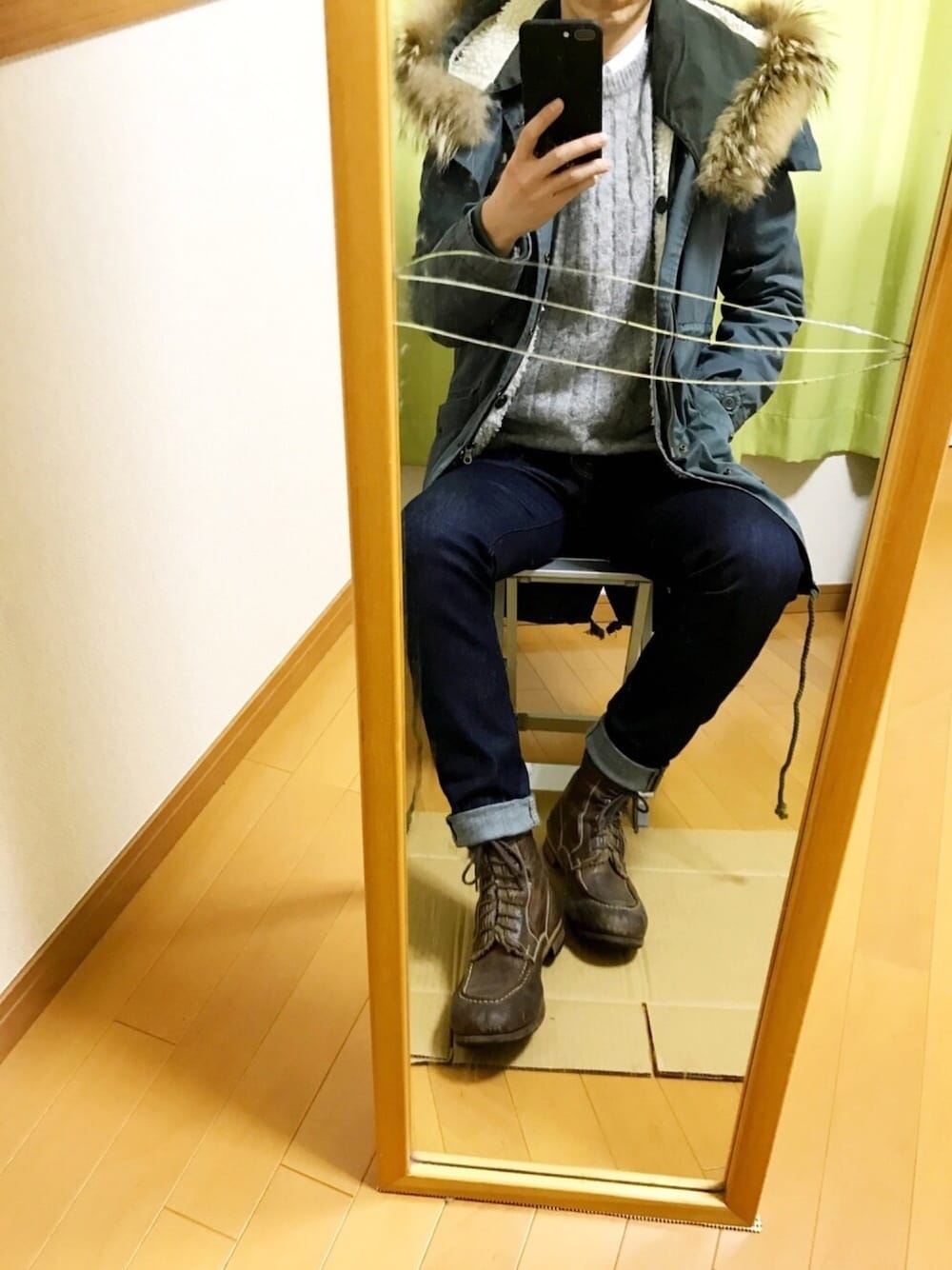 グリーン系のモッズコート、グレー系のニット/セーター、ブルー系のデニムパンツを着用したメンズの冬コーディネートの1枚目の写真