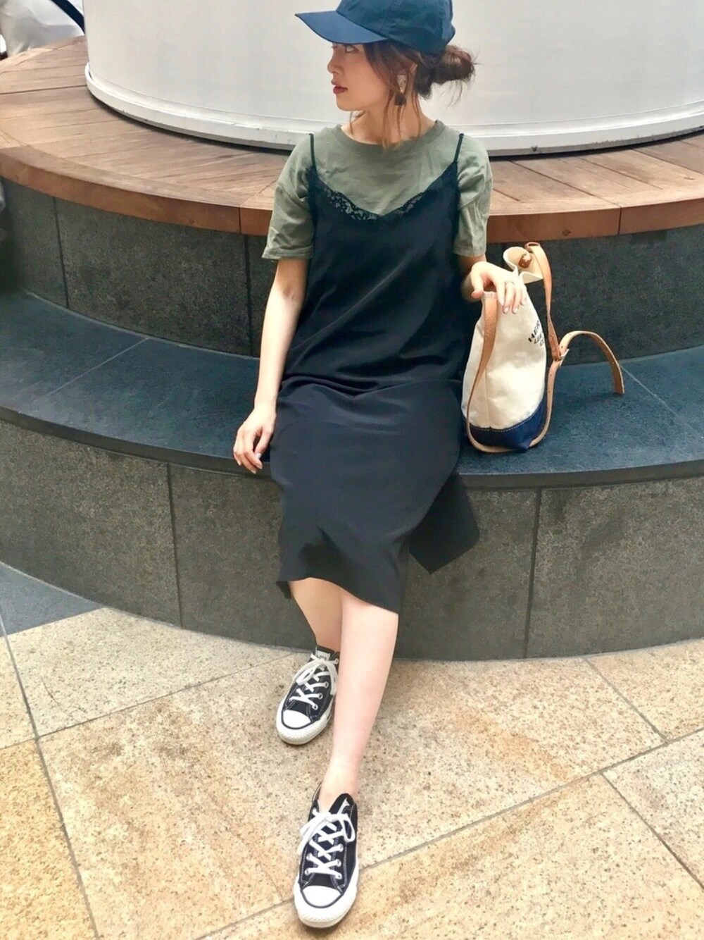 グリーン系のTシャツ/カットソー、ブラック系のワンピース、ブラック系のスニーカーを着用したレディースの秋コーディネートの1枚目の写真
