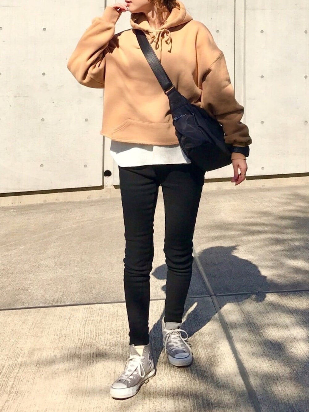ベージュ系のパーカー、ブラック系のボディバッグ/ウエストポーチ、ホワイト系のTシャツ/カットソーを着用したレディースの冬コーディネートの1枚目の写真