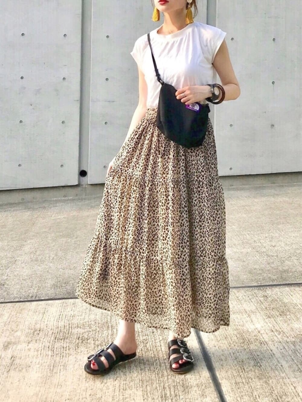 ベージュ系のスカート、ホワイト系のTシャツ/カットソー、ブラック系のバッグを着用したレディースの夏コーディネートの1枚目の写真