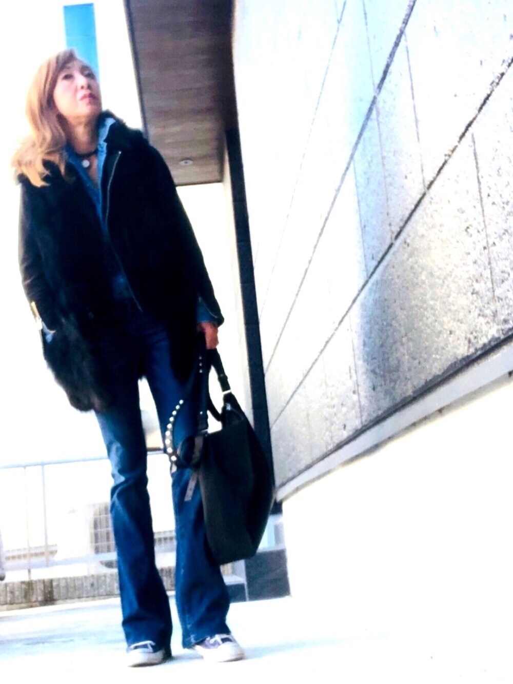 ブラック系のベスト、ブラック系のトートバッグ、ブルー系のデニムパンツを着用したレディースの秋コーディネートの1枚目の写真