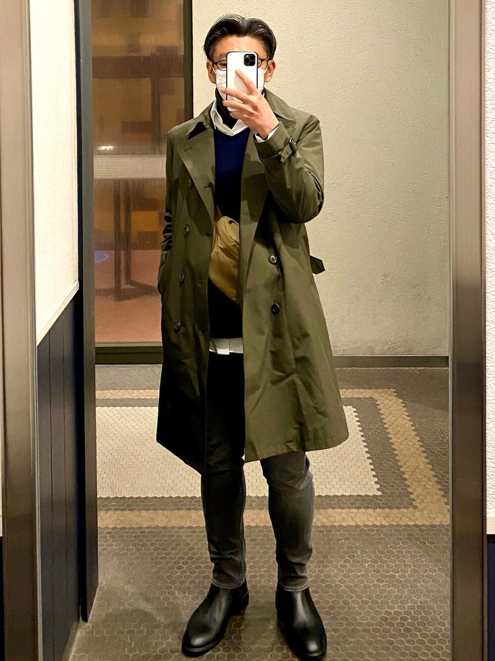 ブラック系のドレスシューズ、グレー系のデニムパンツ、グリーン系のトレンチコートを着用したメンズの冬コーディネートの1枚目の写真