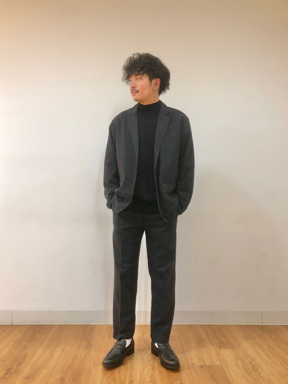 ブラック系のニット/セーター、ブルー系のテーラードジャケット、ブラック系のローファーを着用したメンズの冬コーディネートの1枚目の写真