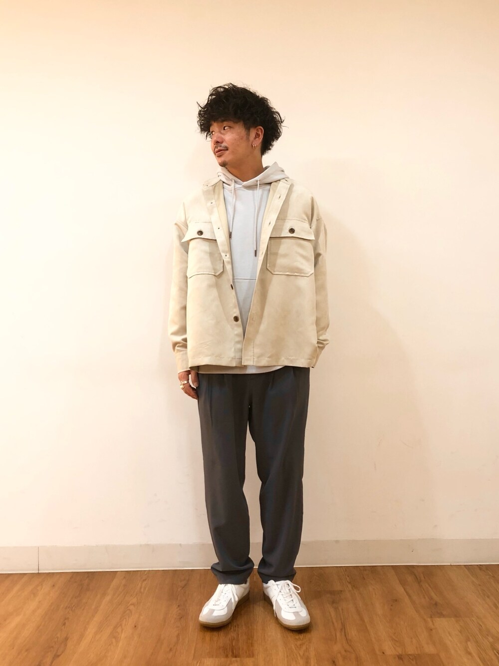 グレー系のスウェット、ベージュ系のシャツ/ブラウス、ホワイト系のスニーカーを着用したメンズの冬コーディネートの1枚目の写真