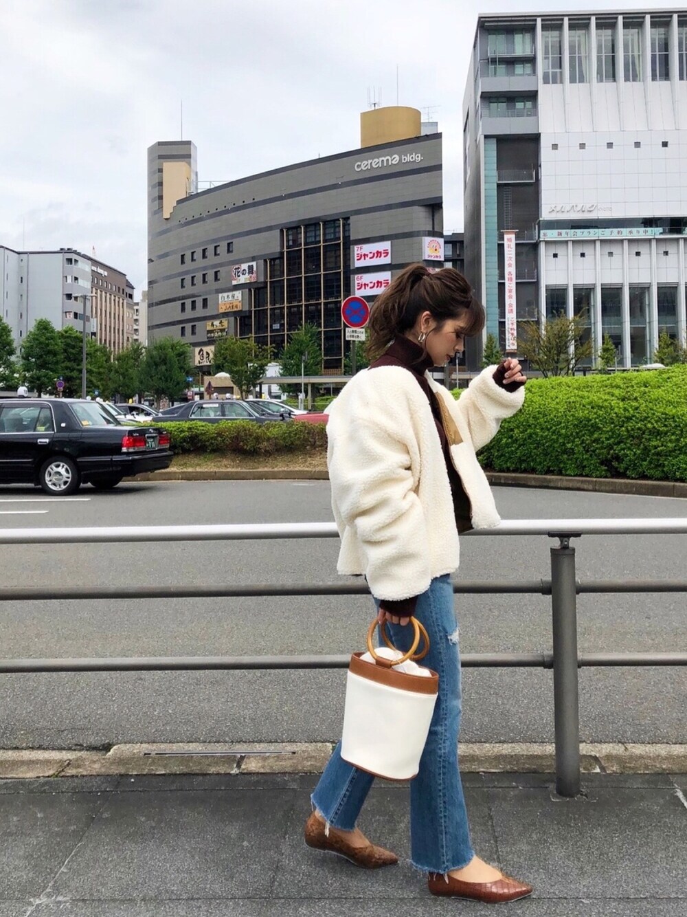 ベージュ系のブルゾン、ブルー系のデニムパンツ、ホワイト系のハンドバッグを着用したレディースの冬コーディネートの1枚目の写真