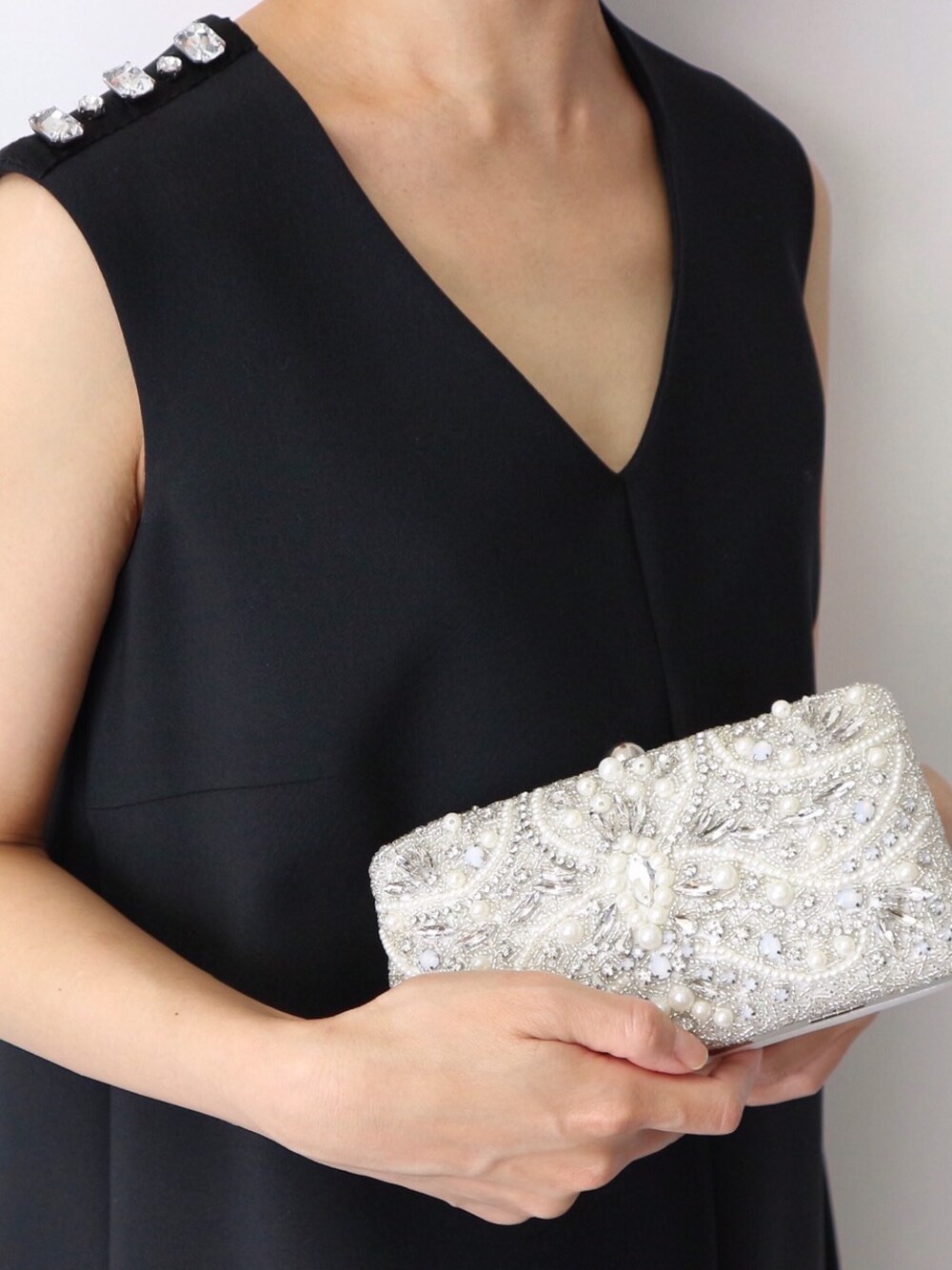 ブラック系のドレス、シルバー系のクラッチバッグを着用したレディースの夏コーディネートの1枚目の写真