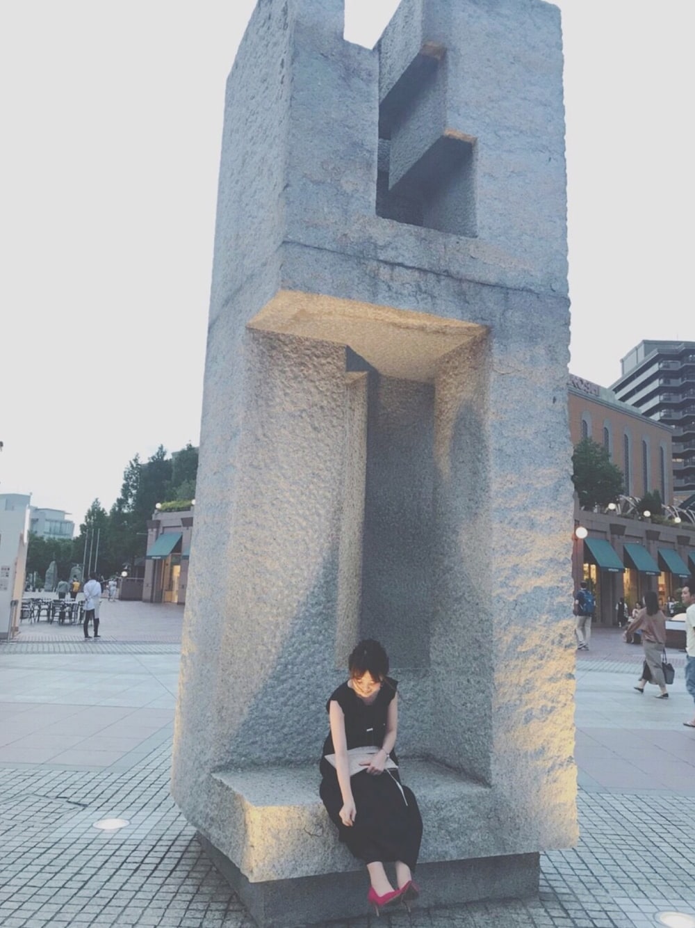 ブラック系のワンピース、ベージュ系のクラッチバッグ、ピンク系のパンプスを着用したレディースの夏コーディネートの1枚目の写真