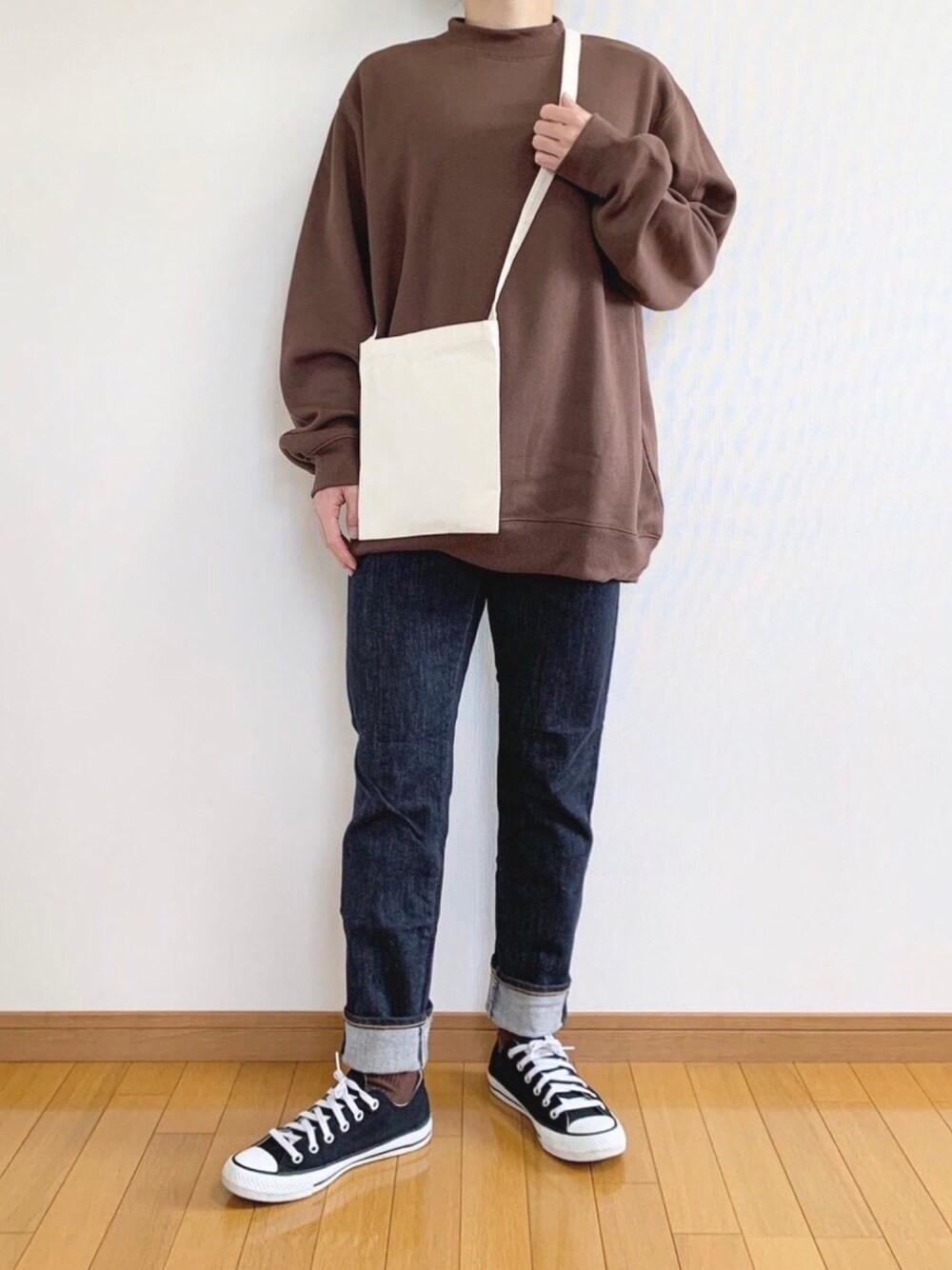 ブラウン系のスウェット、ブラック系のデニムパンツ、ブラック系のスニーカーを着用したメンズの秋コーディネートの1枚目の写真