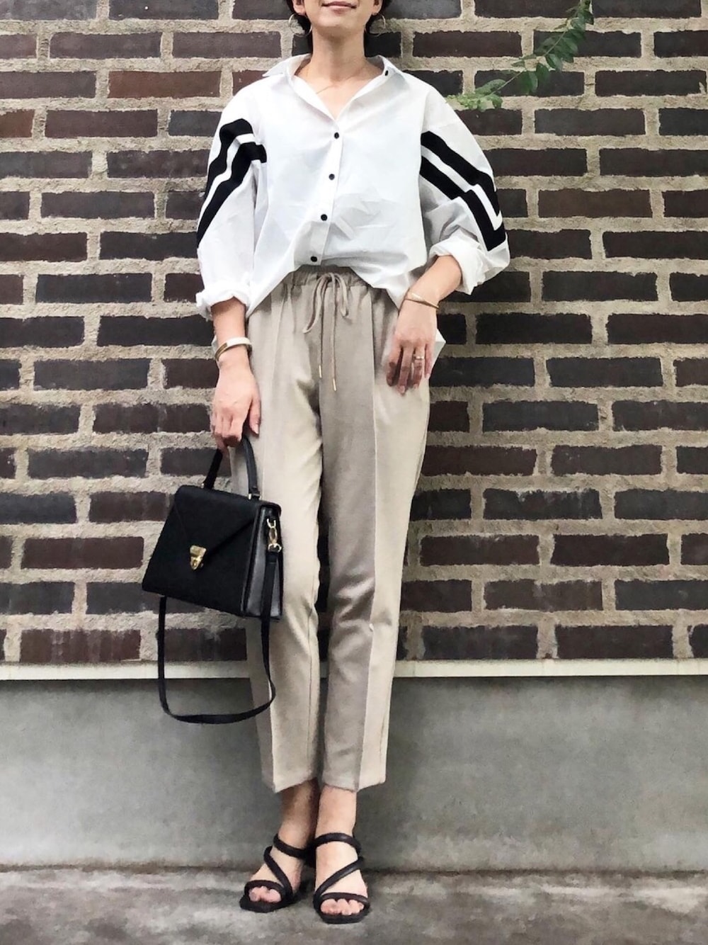 ホワイト系のシャツ/ブラウス、ベージュ系のその他パンツ、ブラック系のサンダルを着用したレディースの夏コーディネートの1枚目の写真