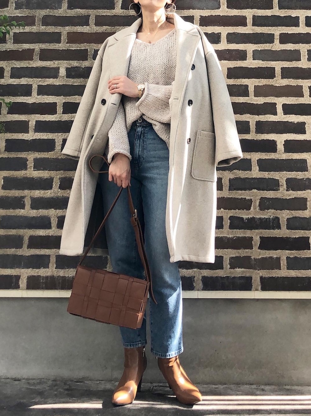 ベージュ系のジャケット/アウター、ベージュ系のニット/セーター、ブルー系のデニムパンツを着用したレディースの冬コーディネートの1枚目の写真