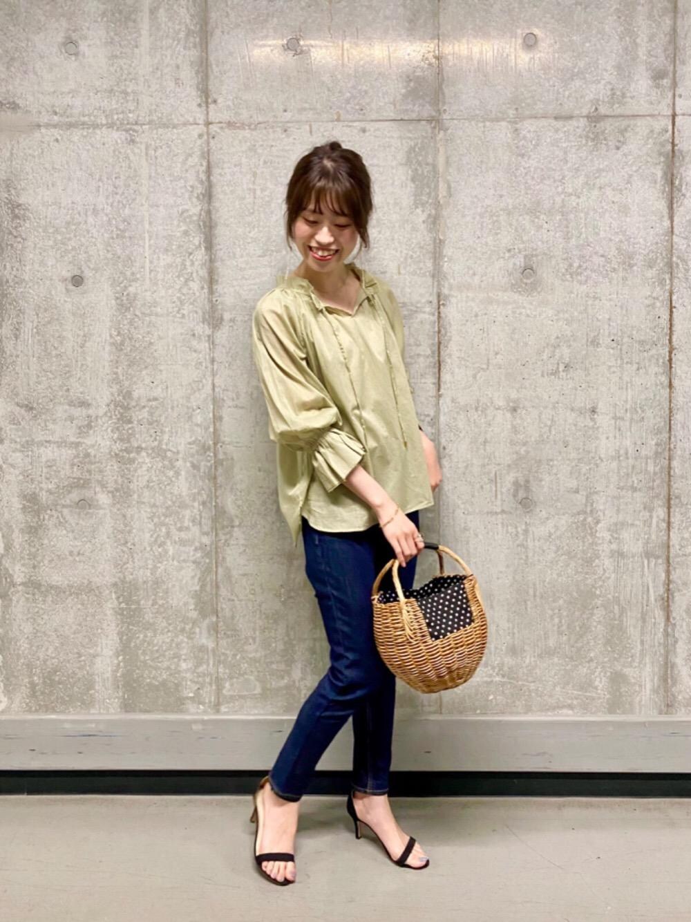 ブルー系のデニムパンツ、ブラック系のかごバッグ、グリーン系のシャツ/ブラウスを着用したレディースの春コーディネートの1枚目の写真