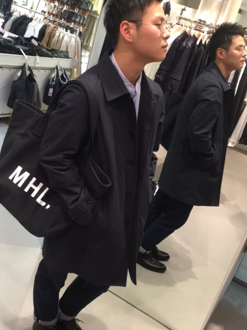 ブラック系のダウンジャケット/コート、ブラック系のトートバッグ、ブルー系のシャツ/ブラウスを着用したメンズの冬コーディネートの1枚目の写真