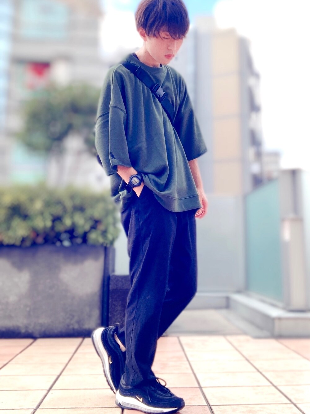 グリーン系のスウェット、ブラック系のボディバッグ/ウエストポーチ、ブラック系のパンツを着用したメンズの夏コーディネートの1枚目の写真