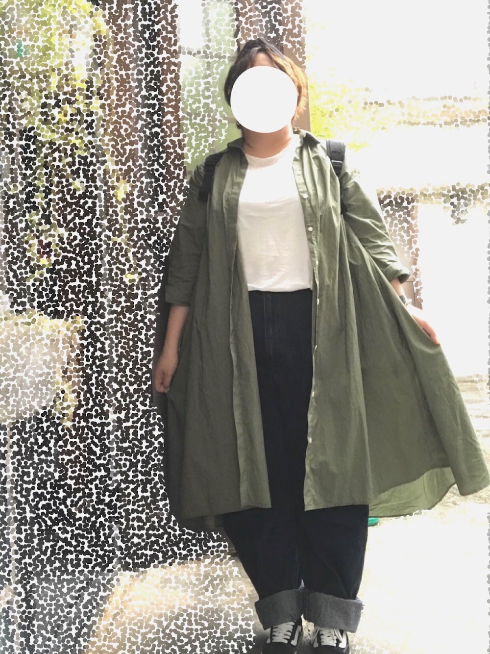 グリーン系のワンピース、ブルー系のデニムパンツ、ブラック系のスニーカーを着用したレディースの春コーディネートの1枚目の写真