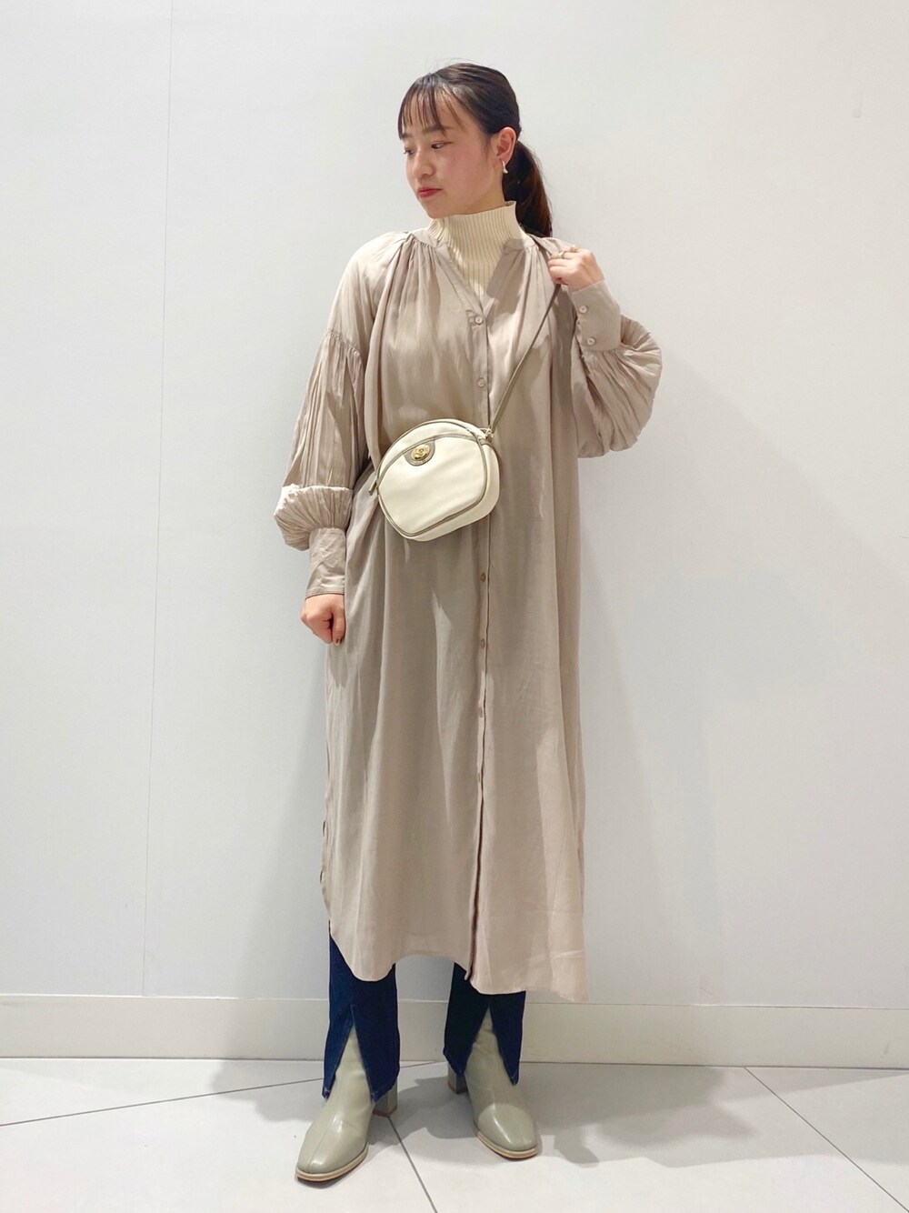 ベージュ系のワンピース、ホワイト系のショルダーバッグ、ホワイト系のニット/セーターを着用したレディースの冬コーディネートの1枚目の写真