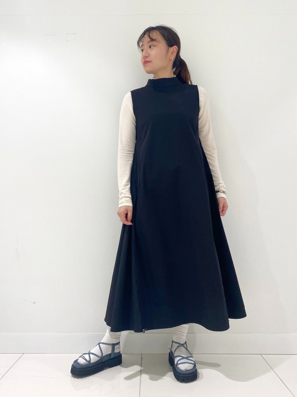 ブラック系のワンピース、ホワイト系のTシャツ/カットソー、ブルー系のサンダルを着用したレディースの春コーディネートの1枚目の写真