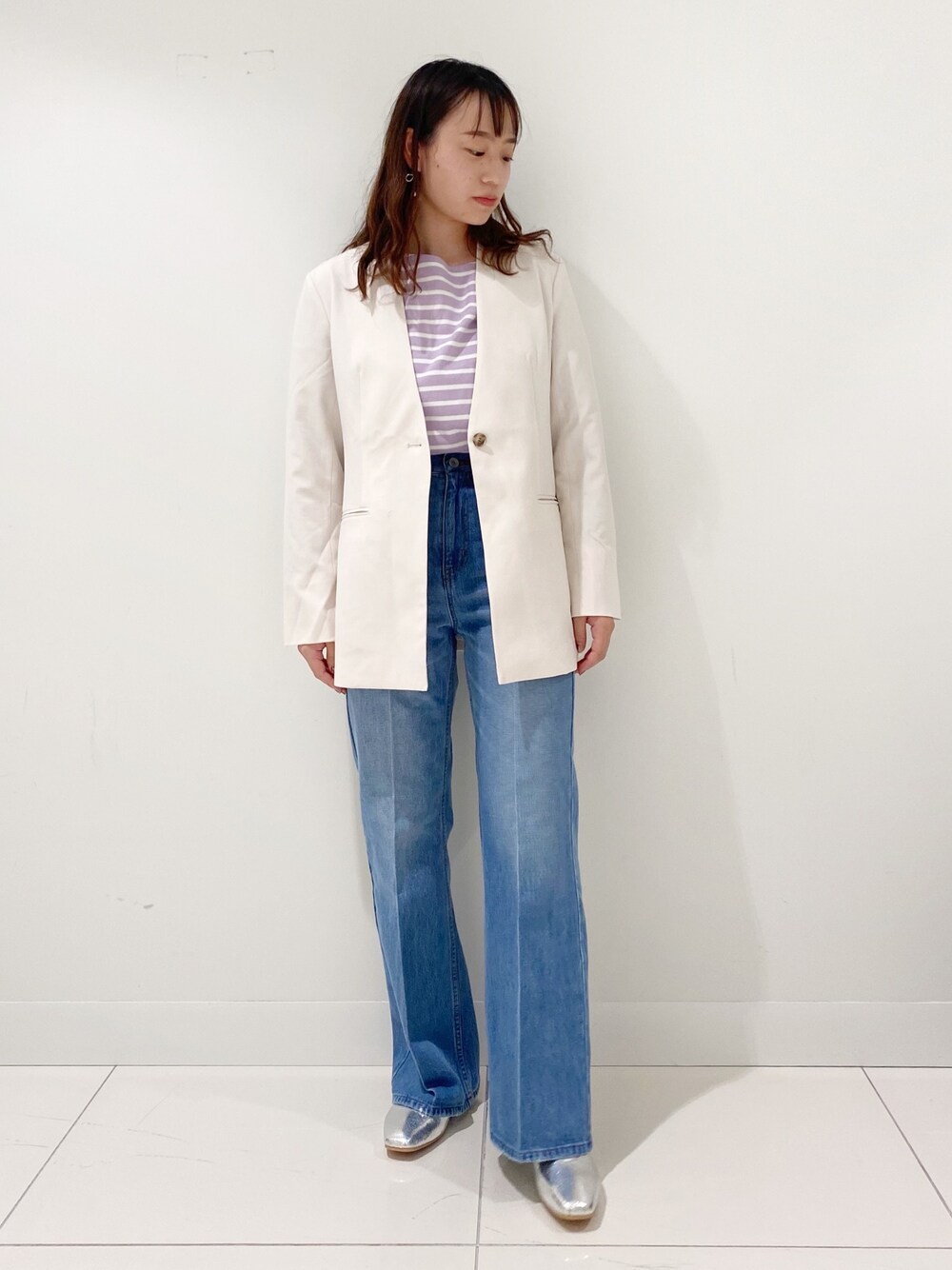 ブルー系のデニムパンツ、ホワイト系のノーカラージャケット、シルバー系のその他シューズを着用したレディースの春コーディネートの1枚目の写真