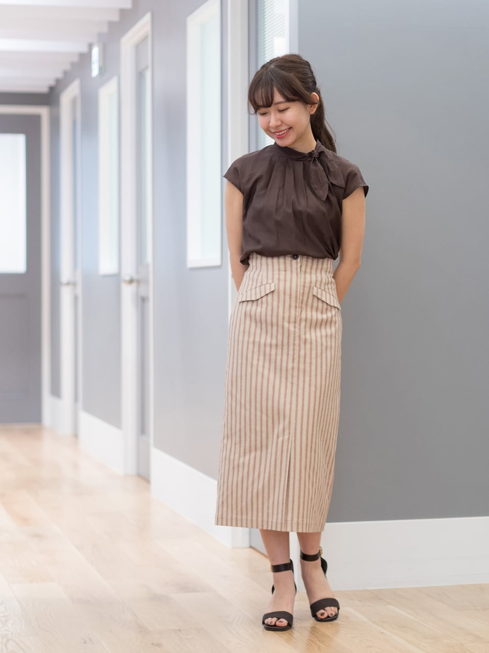 ブラウン系のシャツ/ブラウス、ベージュ系のスカート、ブラウン系のショルダーバッグを着用したレディースの春コーディネートの1枚目の写真