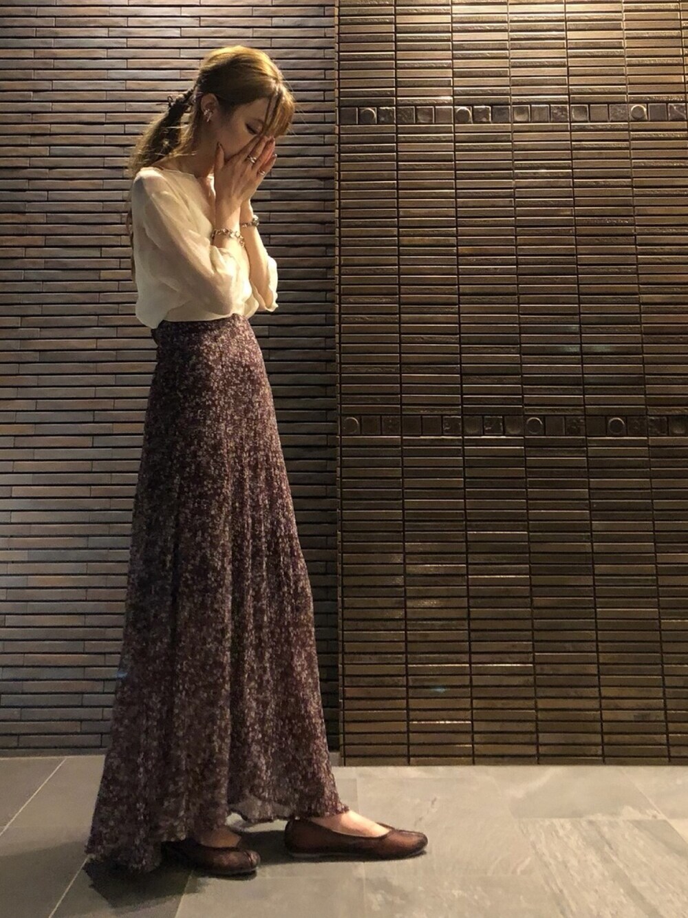 ホワイト系のトップス、ホワイト系のキャミソール、ブラウン系のスカートを着用したレディースの夏コーディネートの1枚目の写真