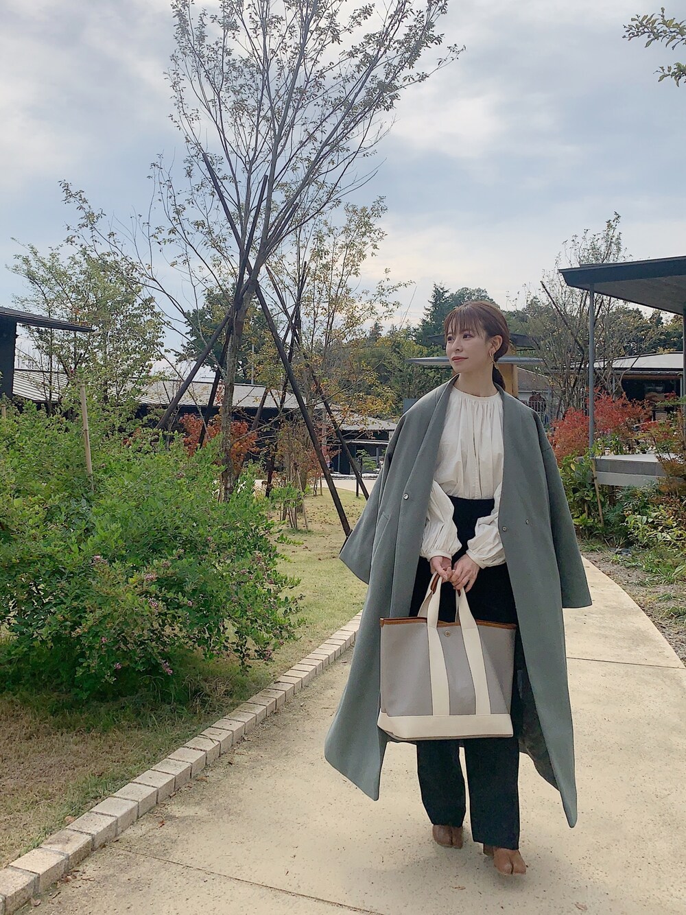 グリーン系のノーカラーコート、ホワイト系のTシャツ/カットソー、ブラウン系のブーツを着用したレディースの秋コーディネートの1枚目の写真