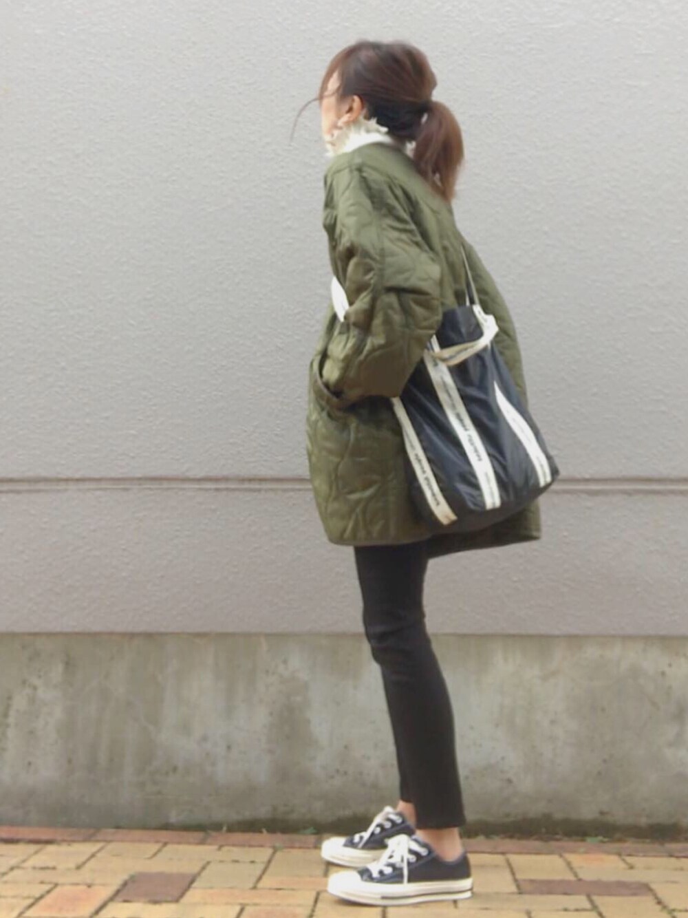 グリーン系のミリタリージャケット、ホワイト系のニット/セーター、ブラック系のデニムパンツを着用したレディースの春コーディネートの1枚目の写真