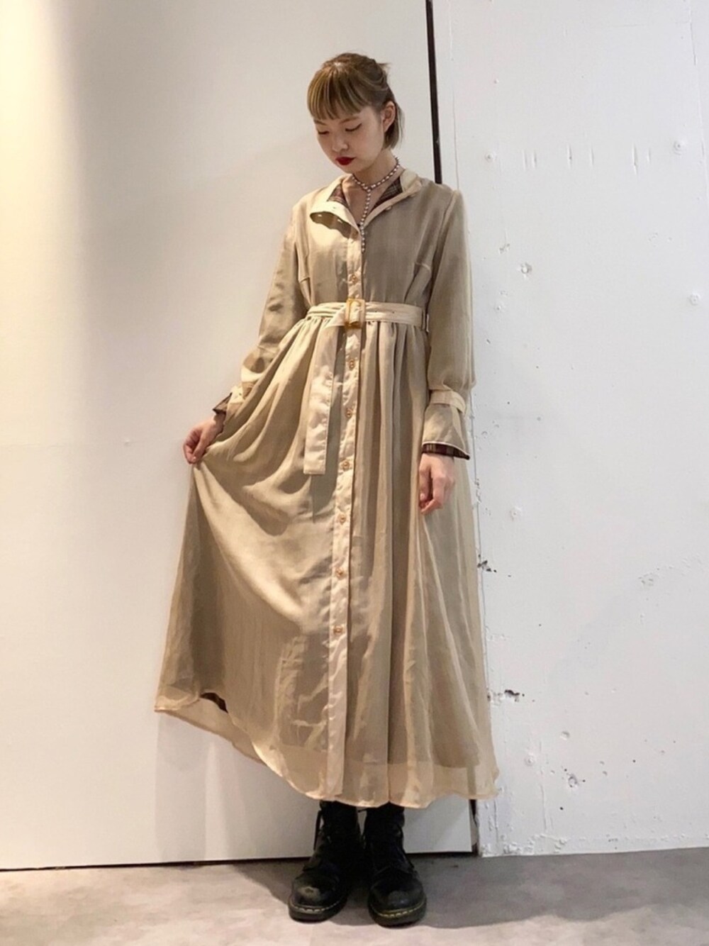 グリーン系のワンピース、ブラック系のブーツを着用したレディースの秋コーディネートの1枚目の写真