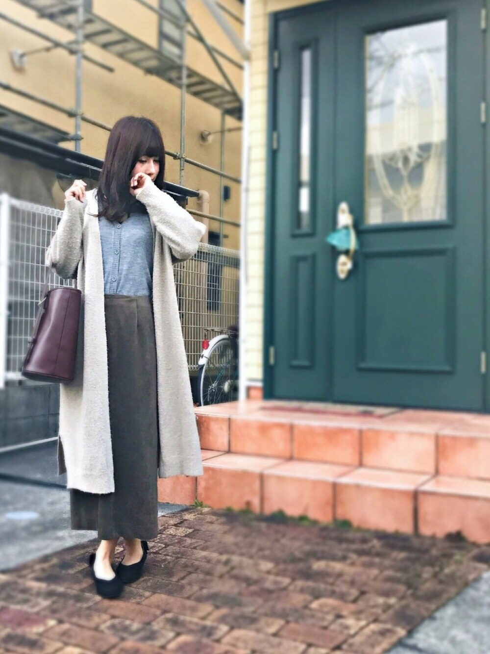 ベージュ系のジャケット/アウター、グレー系のカーディガン/ボレロ、グリーン系のスカートを着用したレディースの冬コーディネートの1枚目の写真