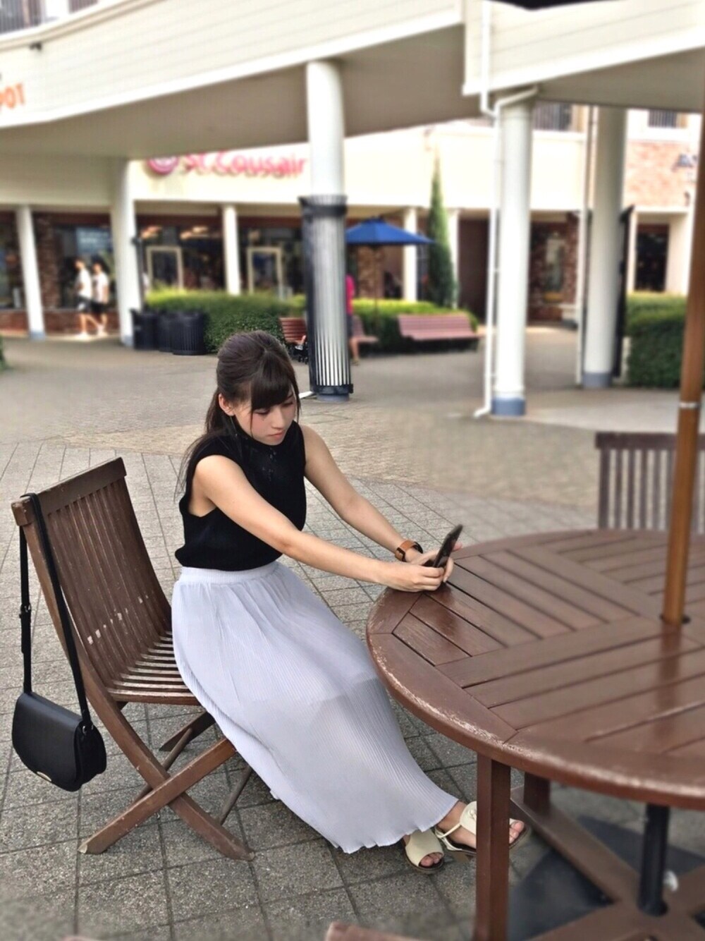 グレー系のスカート、ブラック系のトップス、ホワイト系のシューズを着用したレディースの夏コーディネートの1枚目の写真