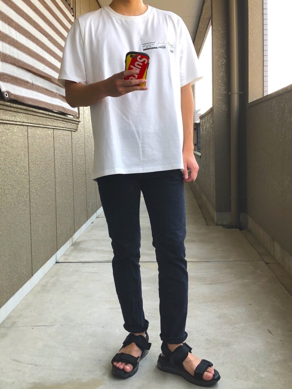ホワイト系のTシャツ/カットソー、ブラック系のデニムパンツ、ブラック系のサンダルを着用したメンズの春コーディネートの1枚目の写真