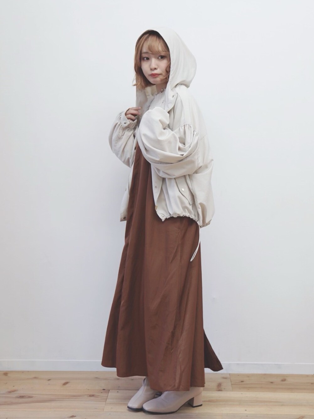 ベージュ系のマウンテンパーカー、ブラウン系のワンピース、ベージュ系のニット/セーターを着用したレディースの秋コーディネートの1枚目の写真