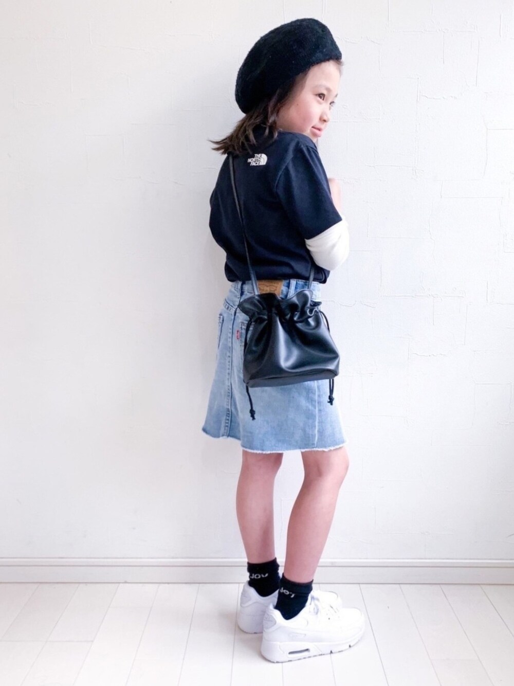 ブラック系のTシャツ/カットソー、ブラック系のハンドバッグ、ホワイト系のスニーカーを着用したキッズの春コーディネートの1枚目の写真