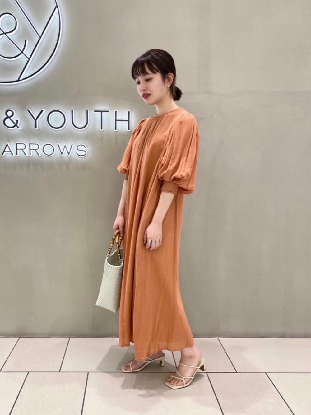 ホワイト系のかごバッグ、オレンジ系のワンピースを着用したレディースの夏コーディネートの1枚目の写真