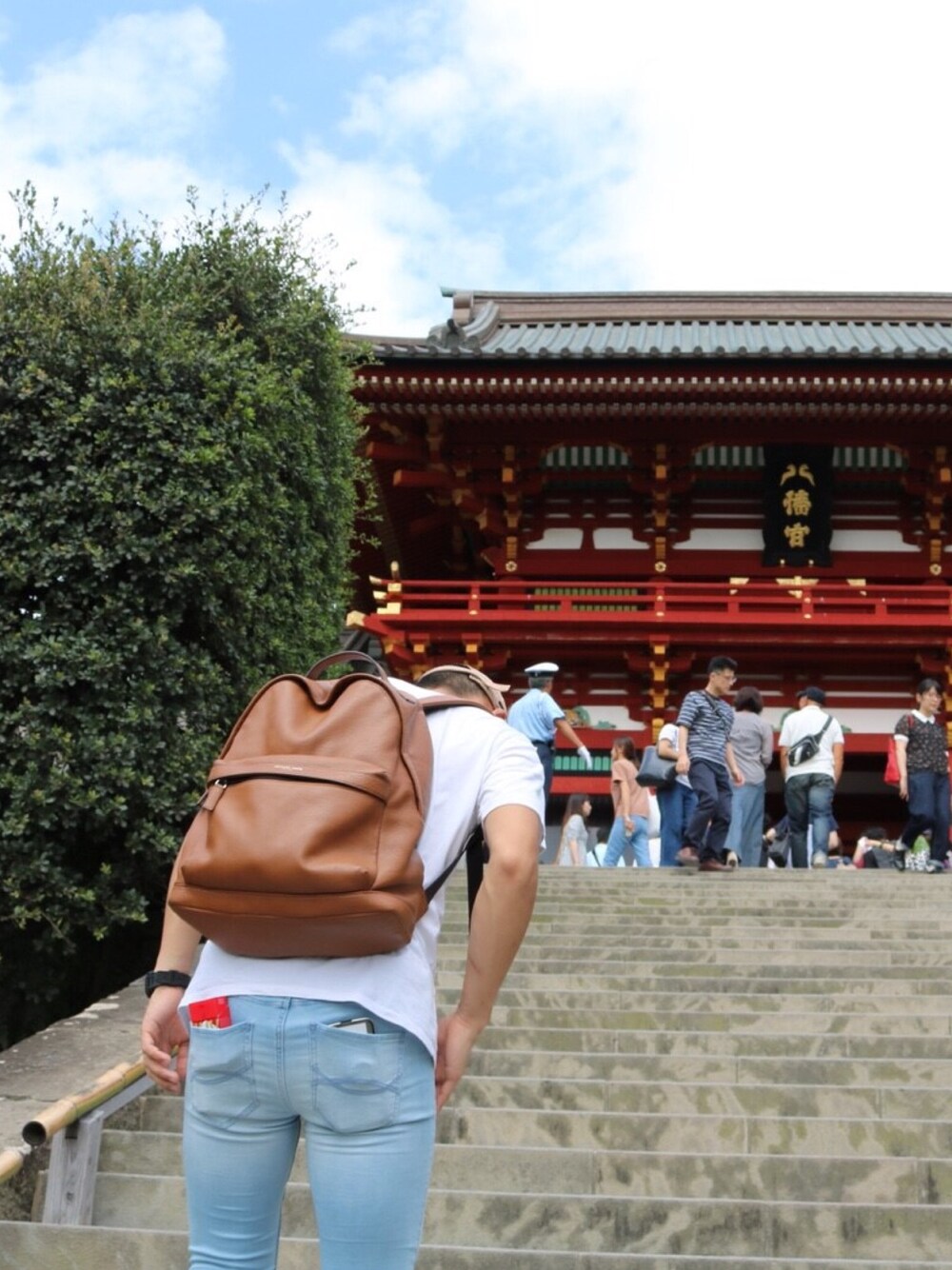 ホワイト系のTシャツ/カットソー、ブルー系のデニムパンツ、ブラウン系のバックパック/リュックを着用したメンズの秋コーディネートの1枚目の写真