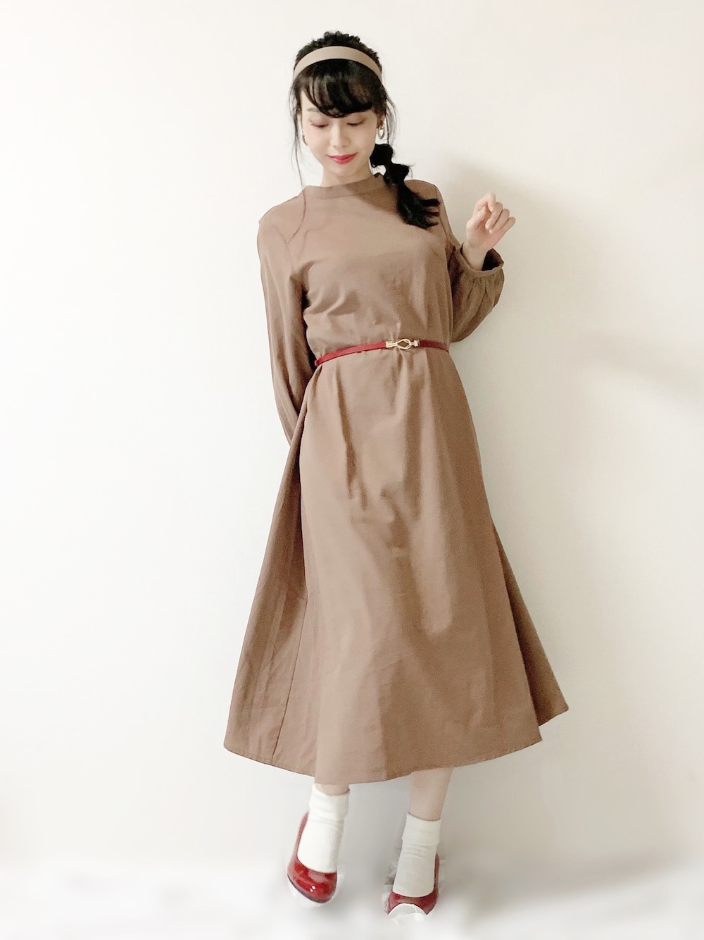 レッド系のパンプス、ブラウン系のワンピース、レッド系のベルトを着用したレディースの冬コーディネートの1枚目の写真