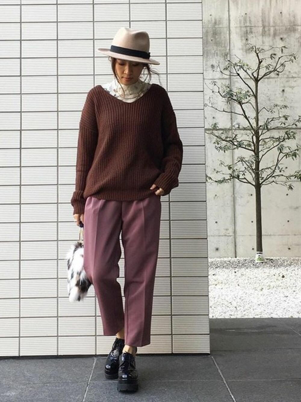 ブラウン系のニット/セーター、ブラック系のハンドバッグを着用したレディースの冬コーディネートの1枚目の写真