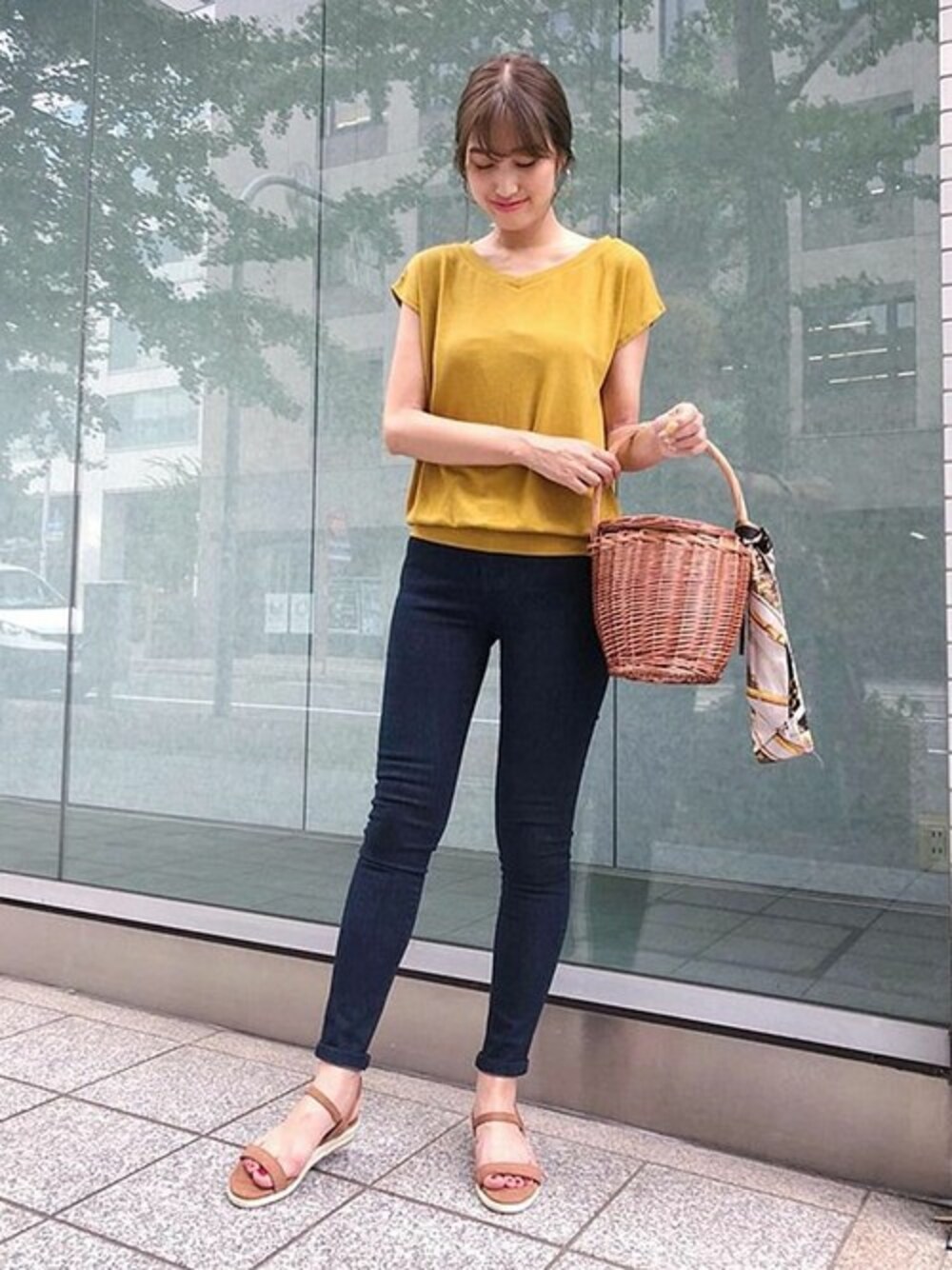 イエロー系のニット/セーター、ブルー系のデニムパンツ、ブラウン系のかごバッグを着用したレディースの夏コーディネートの1枚目の写真
