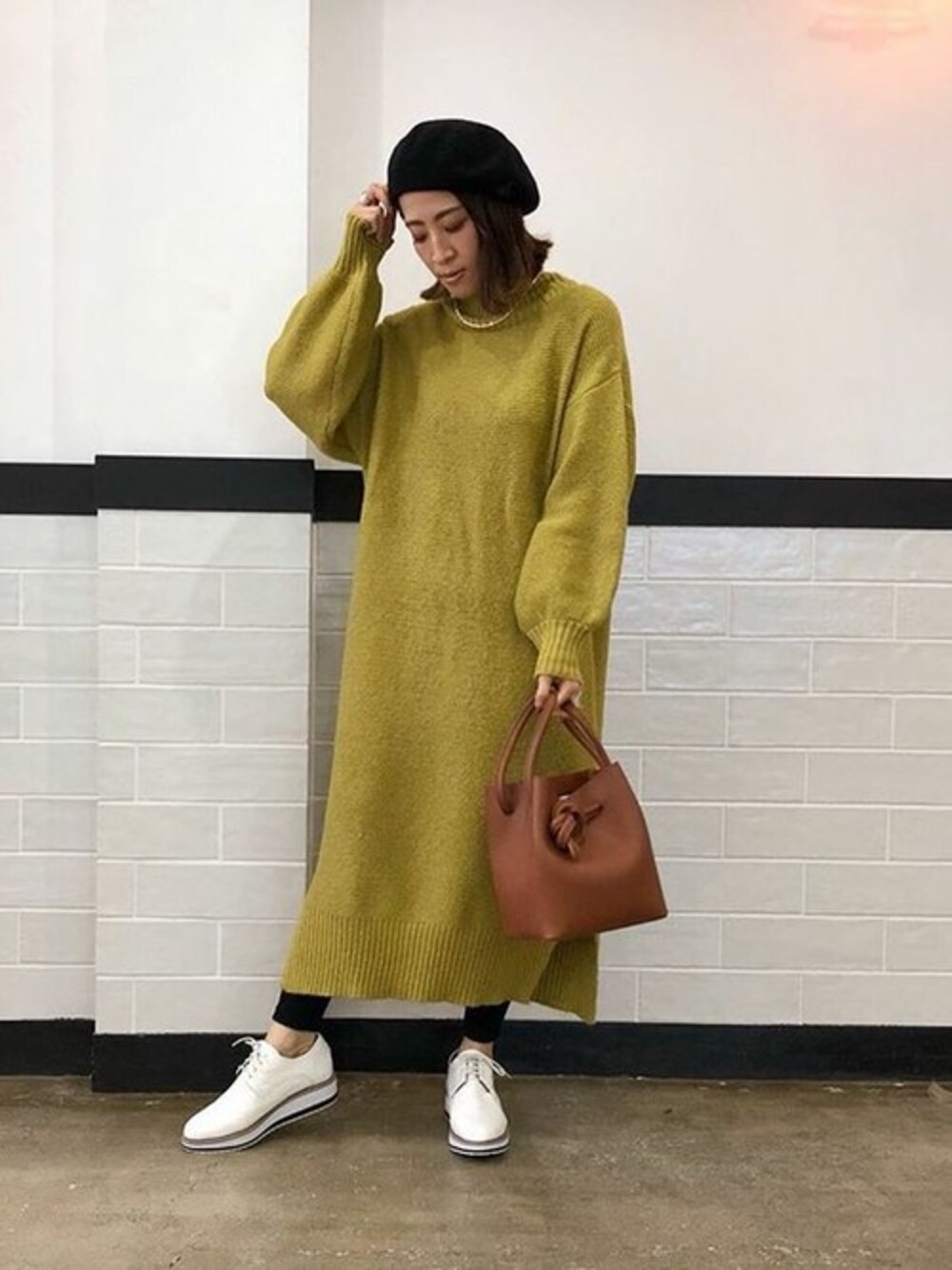 イエロー系のワンピース、ホワイト系のその他シューズ、ブラック系のレギンス/スパッツを着用したレディースの冬コーディネートの1枚目の写真