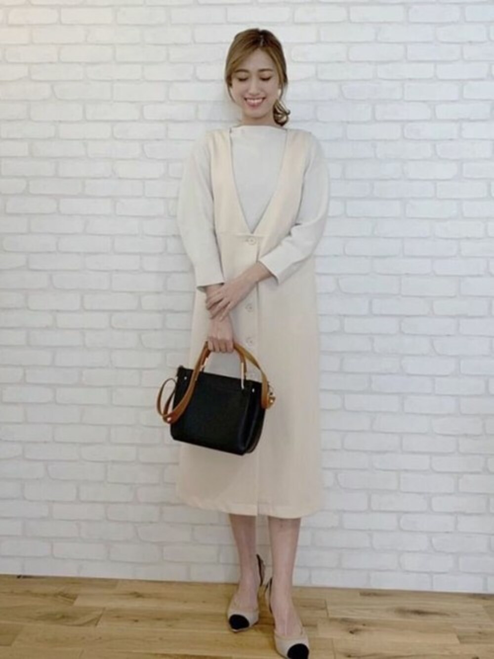 ホワイト系のジャンパースカート、ホワイト系のニット/セーター、ブラック系のパンプスを着用したレディースの冬コーディネートの1枚目の写真