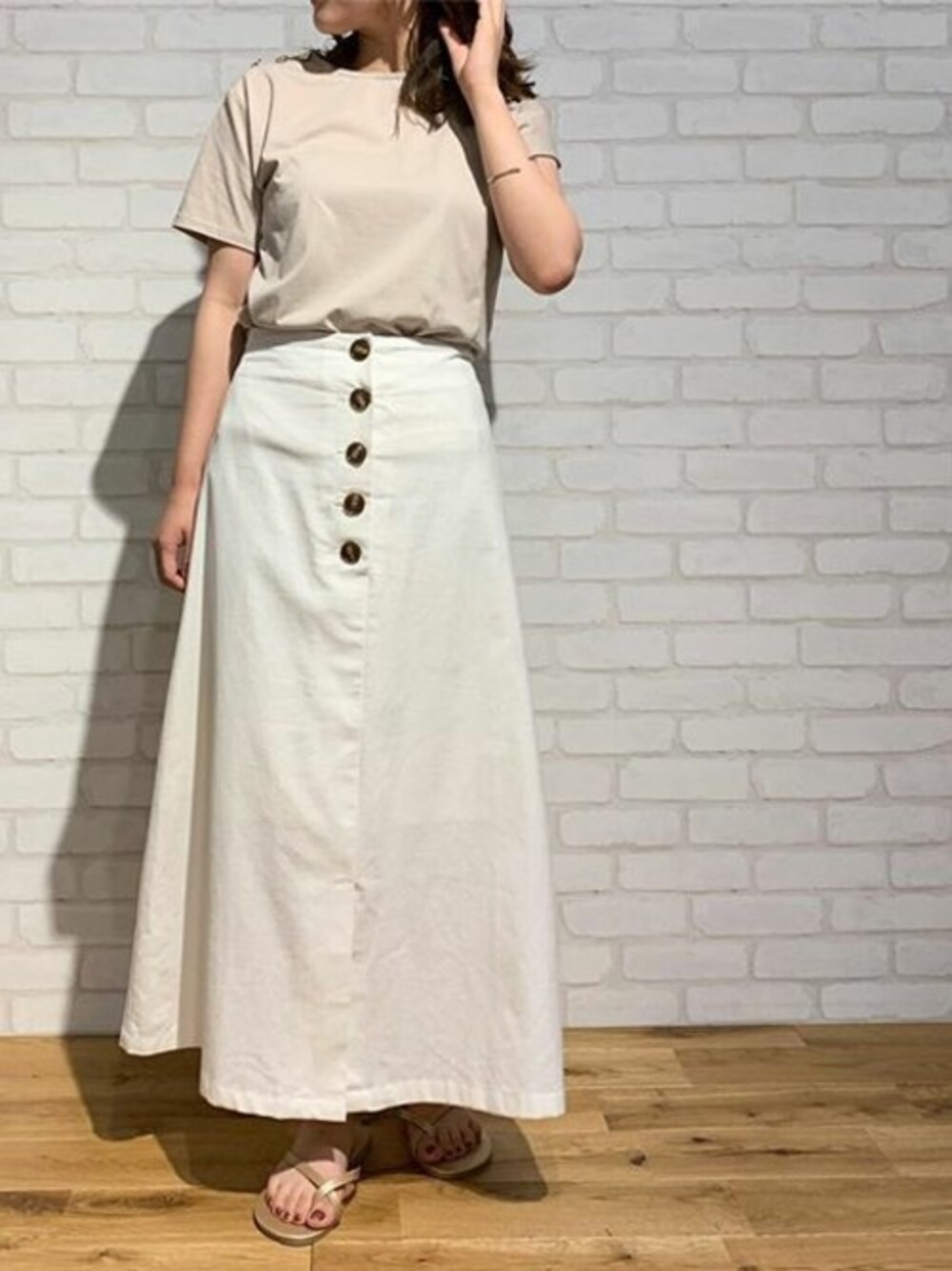ホワイト系のスカート、ベージュ系のTシャツ/カットソー、ゴールド系のサンダルを着用したレディースの夏コーディネートの1枚目の写真