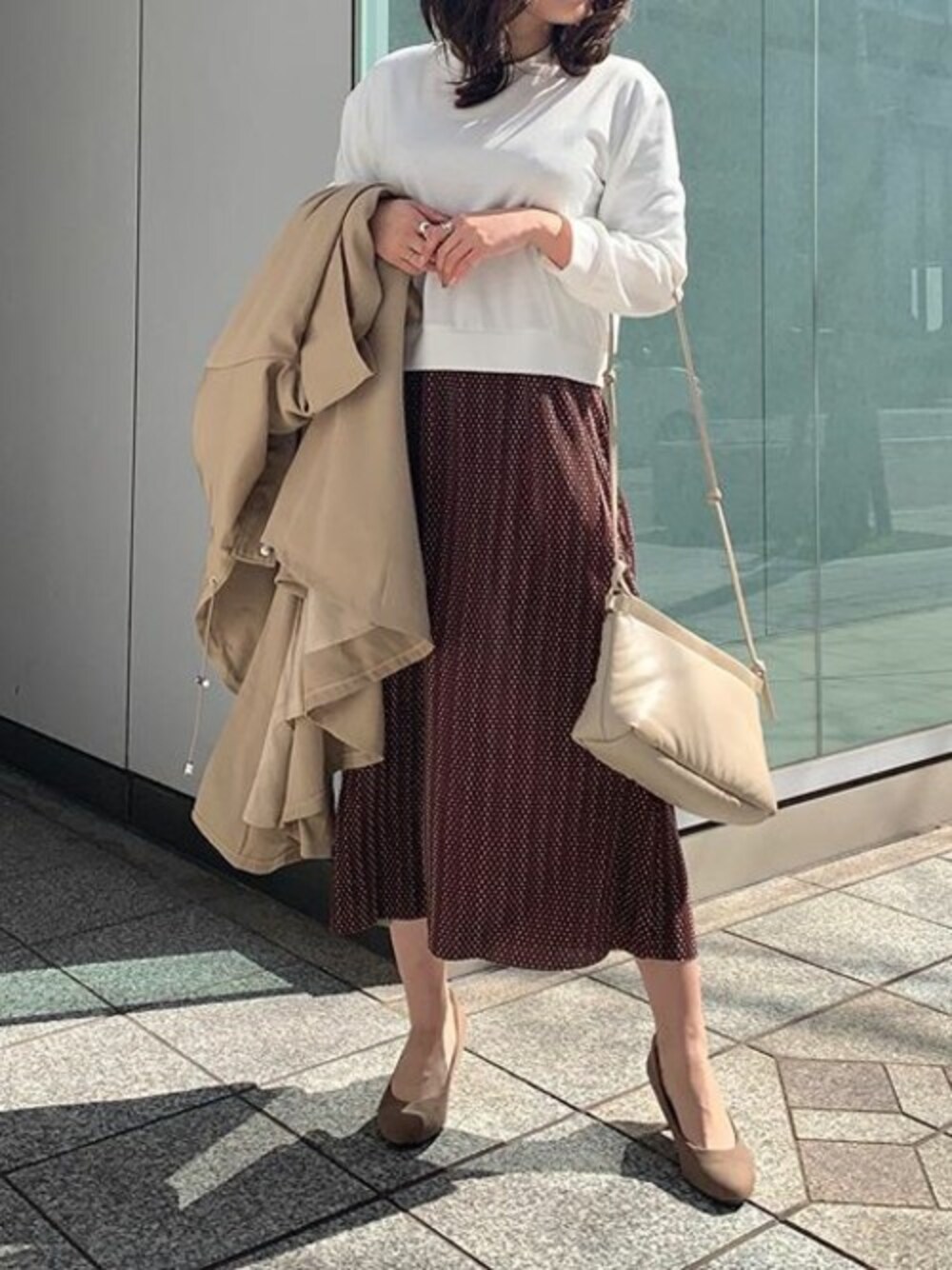 ベージュ系のマウンテンパーカー、ベージュ系のクラッチバッグ、ベージュ系のパンプスを着用したレディースの冬コーディネートの1枚目の写真
