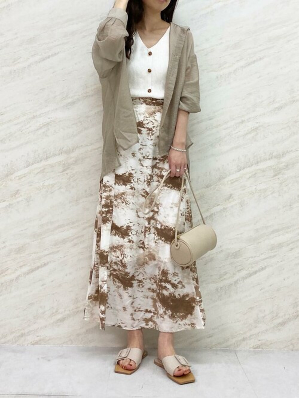 ホワイト系のニット/セーター、ベージュ系のスカート、ホワイト系のショルダーバッグを着用したレディースの夏コーディネートの1枚目の写真