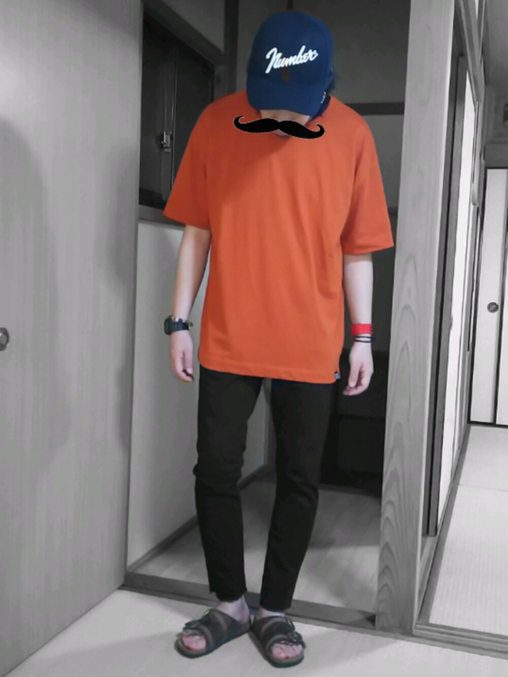 オレンジ系のTシャツ/カットソー、ブラック系のデニムパンツ、ブラウン系のサンダルを着用したメンズの夏コーディネートの1枚目の写真