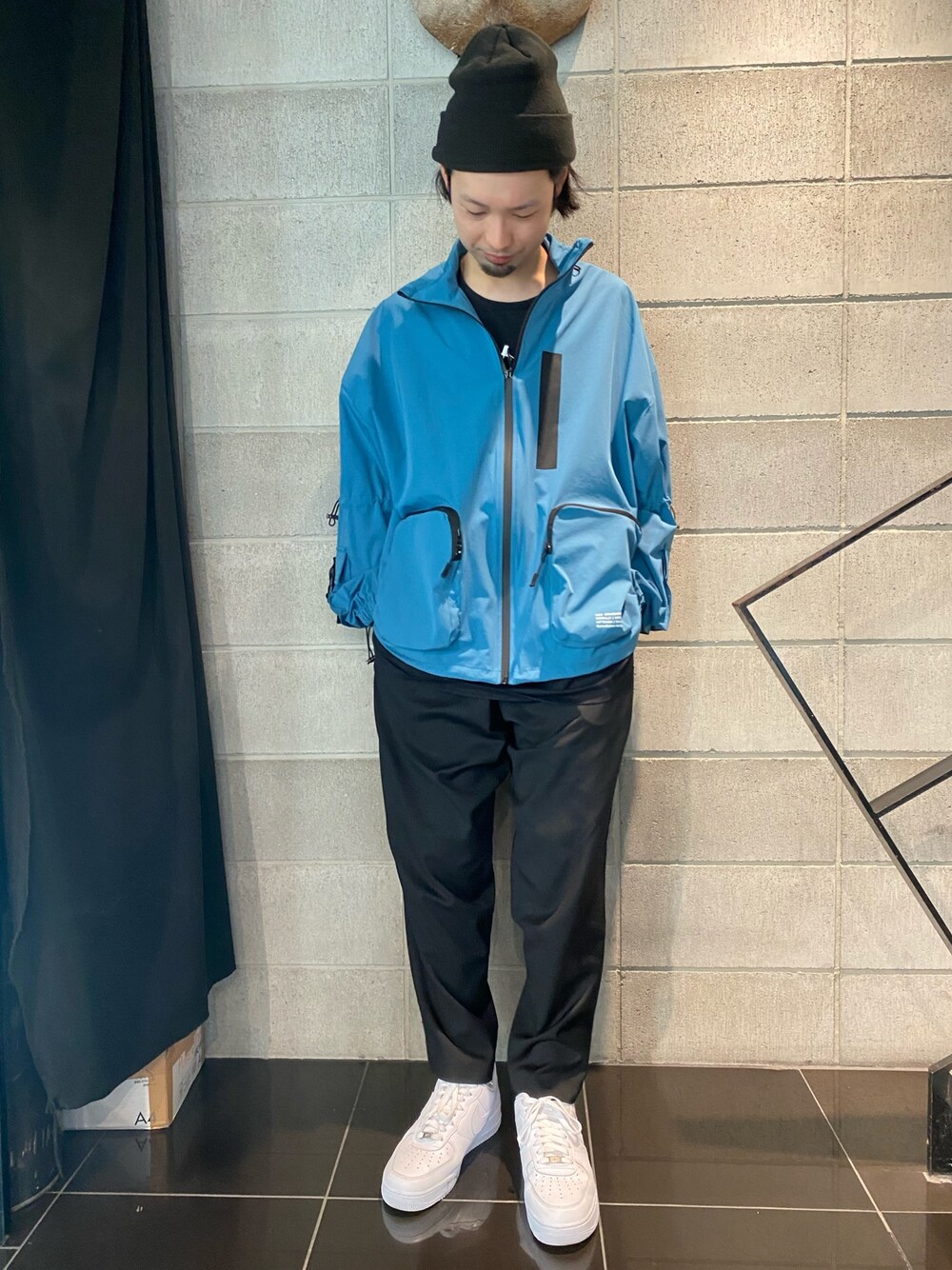 ホワイト系のスニーカー、ブラック系のスラックス、ブルー系のブルゾンを着用したメンズの春コーディネートの1枚目の写真