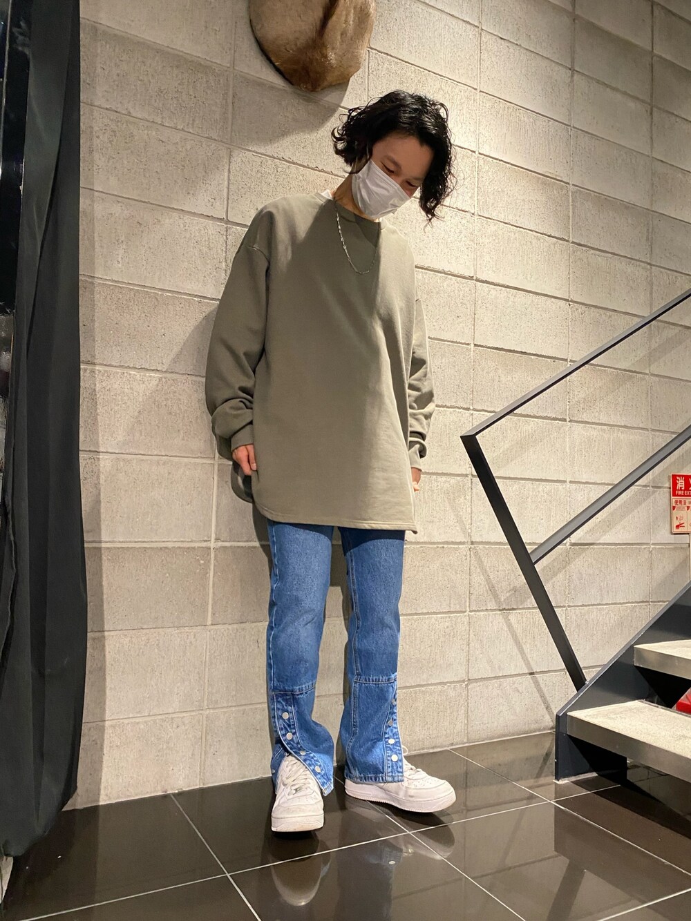 ブルー系のデニムパンツ、グリーン系のスウェット、ホワイト系のスニーカーを着用したメンズの冬コーディネートの1枚目の写真