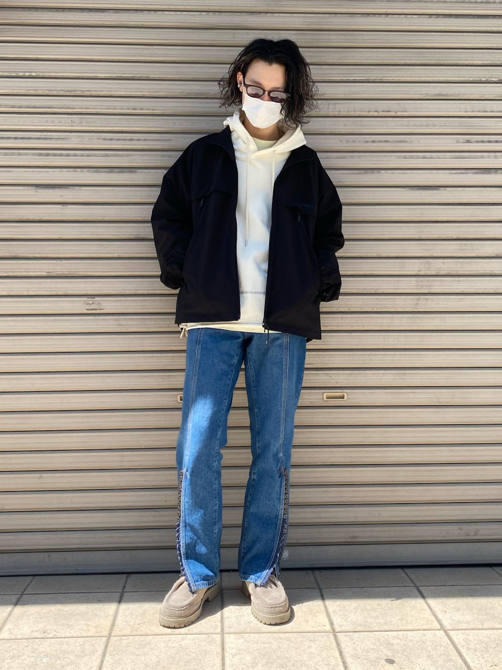 ブルー系のデニムパンツ、ホワイト系のパーカー、ブラック系のブルゾンを着用したメンズの春コーディネートの1枚目の写真