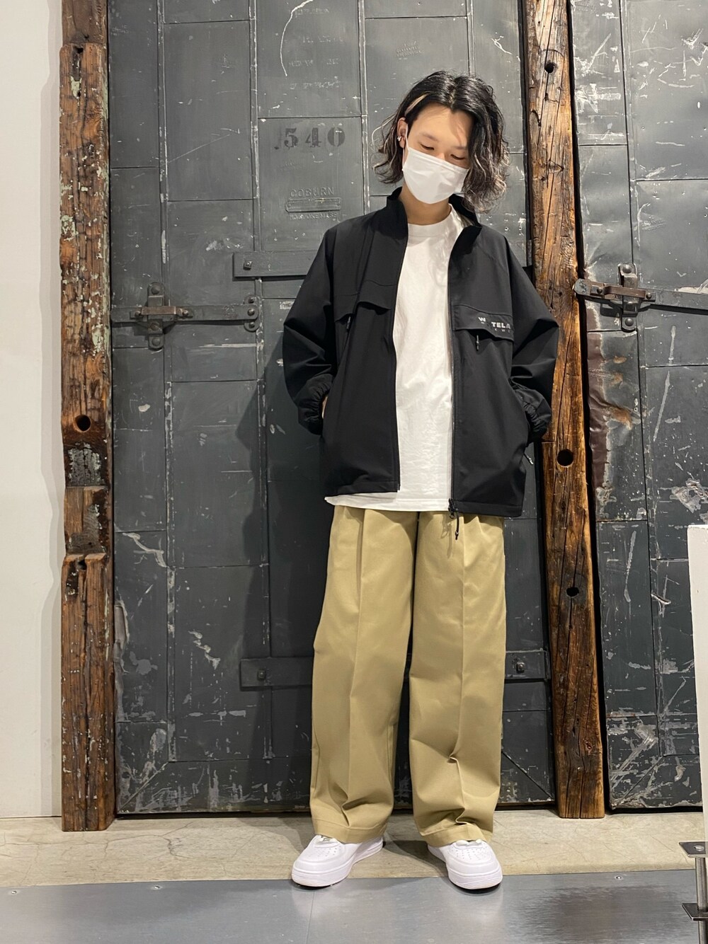 ブラック系のブルゾン、ベージュ系のチノパンツ、ホワイト系のスニーカーを着用したメンズの春コーディネートの1枚目の写真