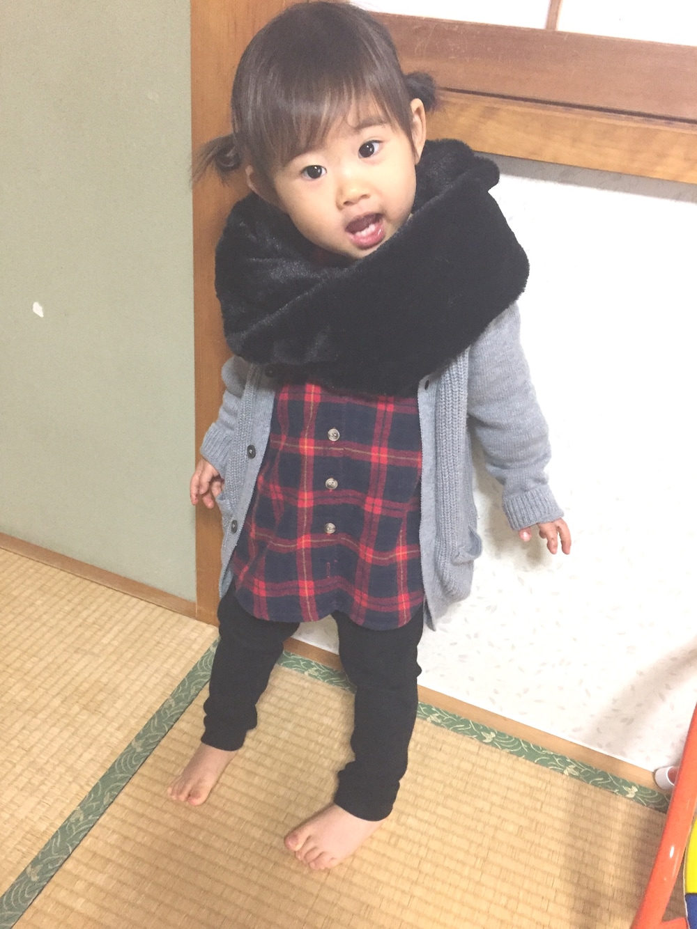 ブラック系のパンツ、グレー系のカーディガン/ボレロ、レッド系のシャツ/ブラウスを着用したキッズの冬コーディネートの1枚目の写真